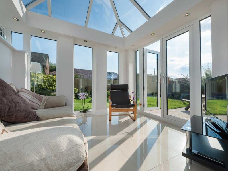 A modern conservatory with white double glazing patio doors.